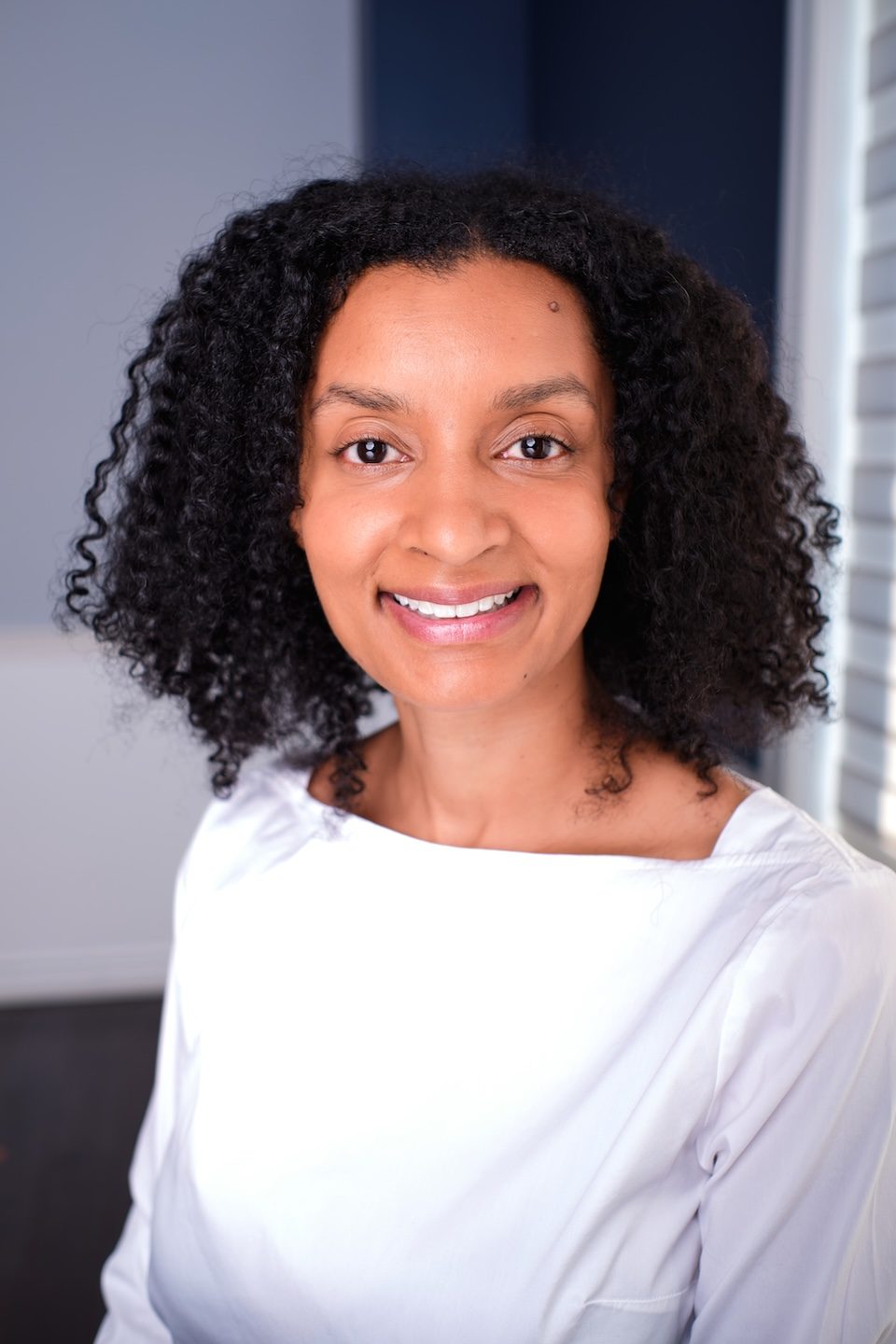 Smiling woman in a white top, natural window light